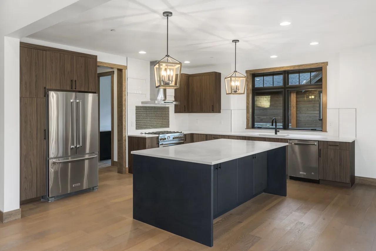 Kitchen featuring dark wood cabinetry, a central island, pendant lights, and stainless steel appliances.
