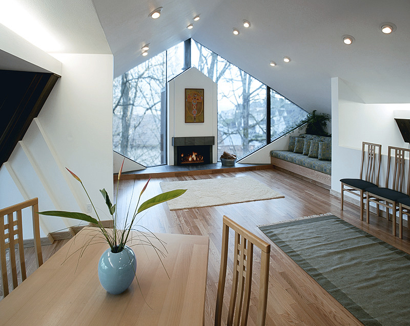 The Fennel Residence features a wood-floored living room with floor-to-ceiling triangular windows and a fireplace.