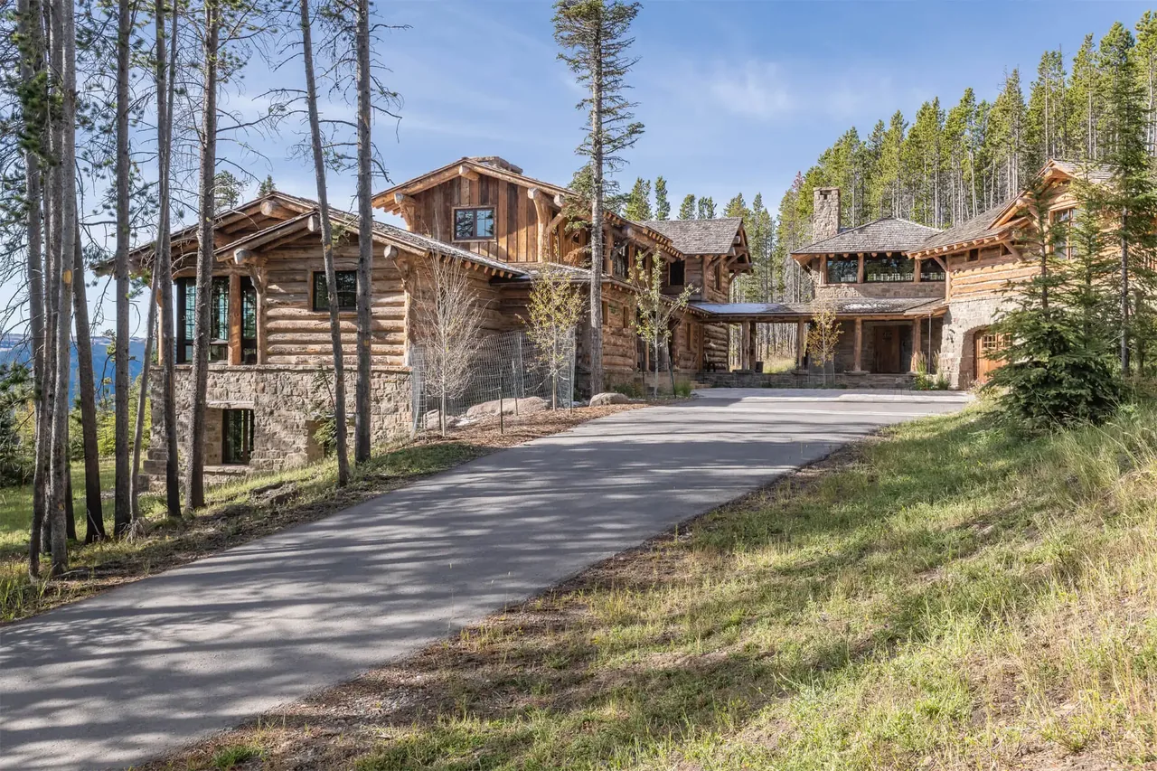 Chalet Redux features a rustic log exterior with stone foundation, surrounded by forest and mountain views.