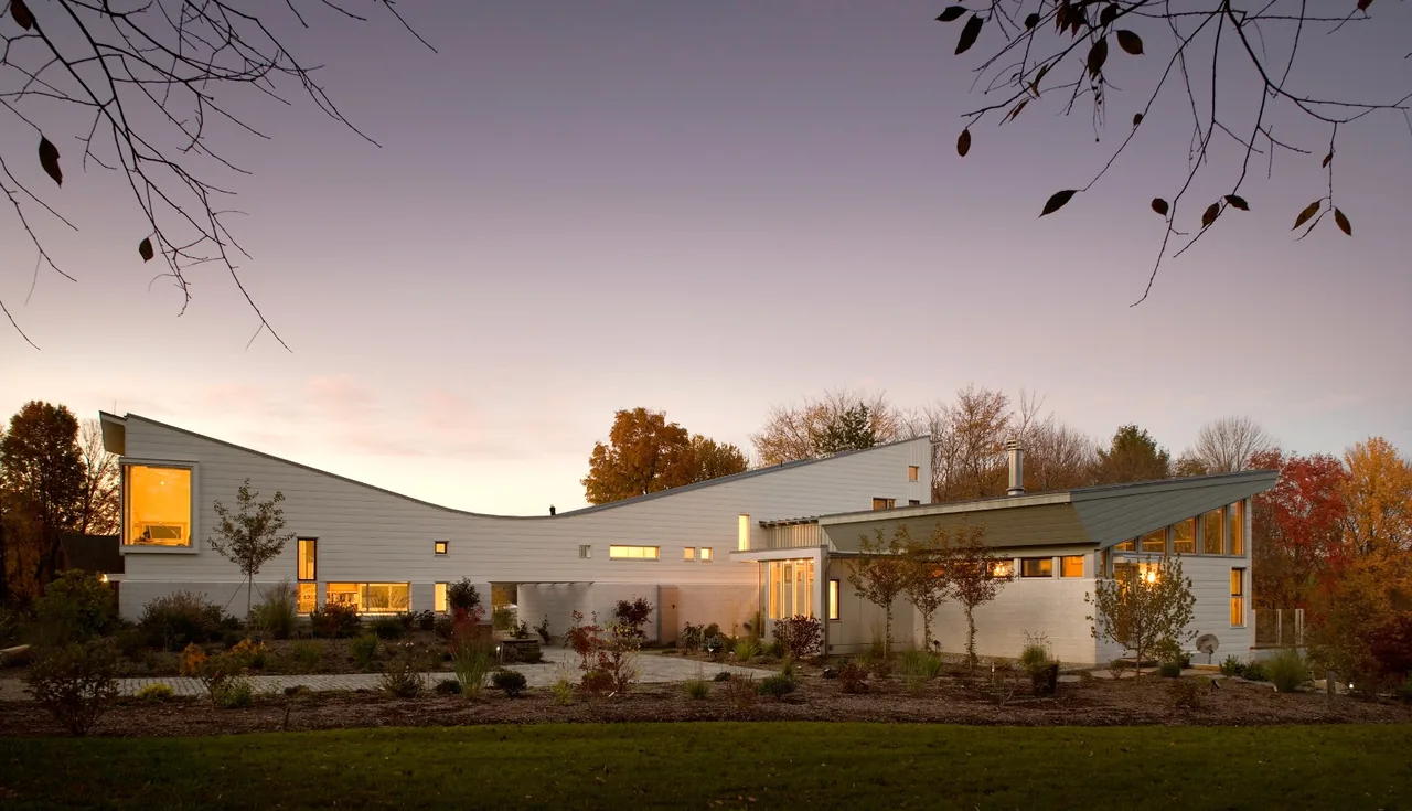 Copy of Crotty Hall features a modern exterior with sweeping sloped roofs and white siding, set in landscaped grounds.