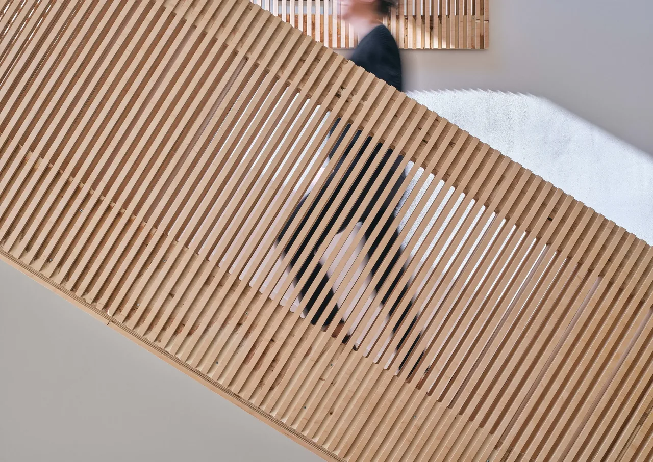 Wooden slatted railing provides a modern design element on a stair in the Steel Louise project.