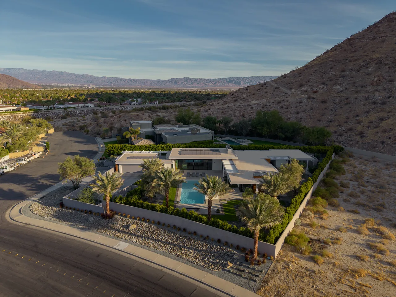 Sky Ridge features a modern home with a pool and landscaped yard beside a desert hill with mountain views.