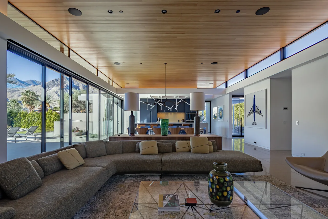 Contemporary living area with floor-to-ceiling glass sliding doors opening to a patio with mountain views