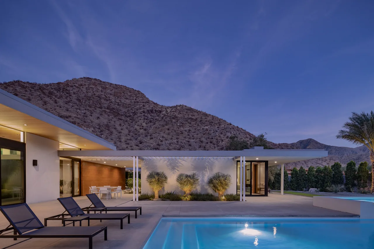 Sky Ridge house by o2 Archtecture features a flat roof, concrete patio, and outdoor seating area with mountain views.