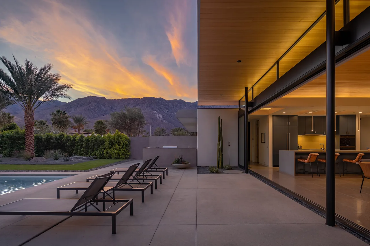 Sky Ridge features a concrete patio with lounge seating opening to a modern kitchen interior against a mountain backdrop.