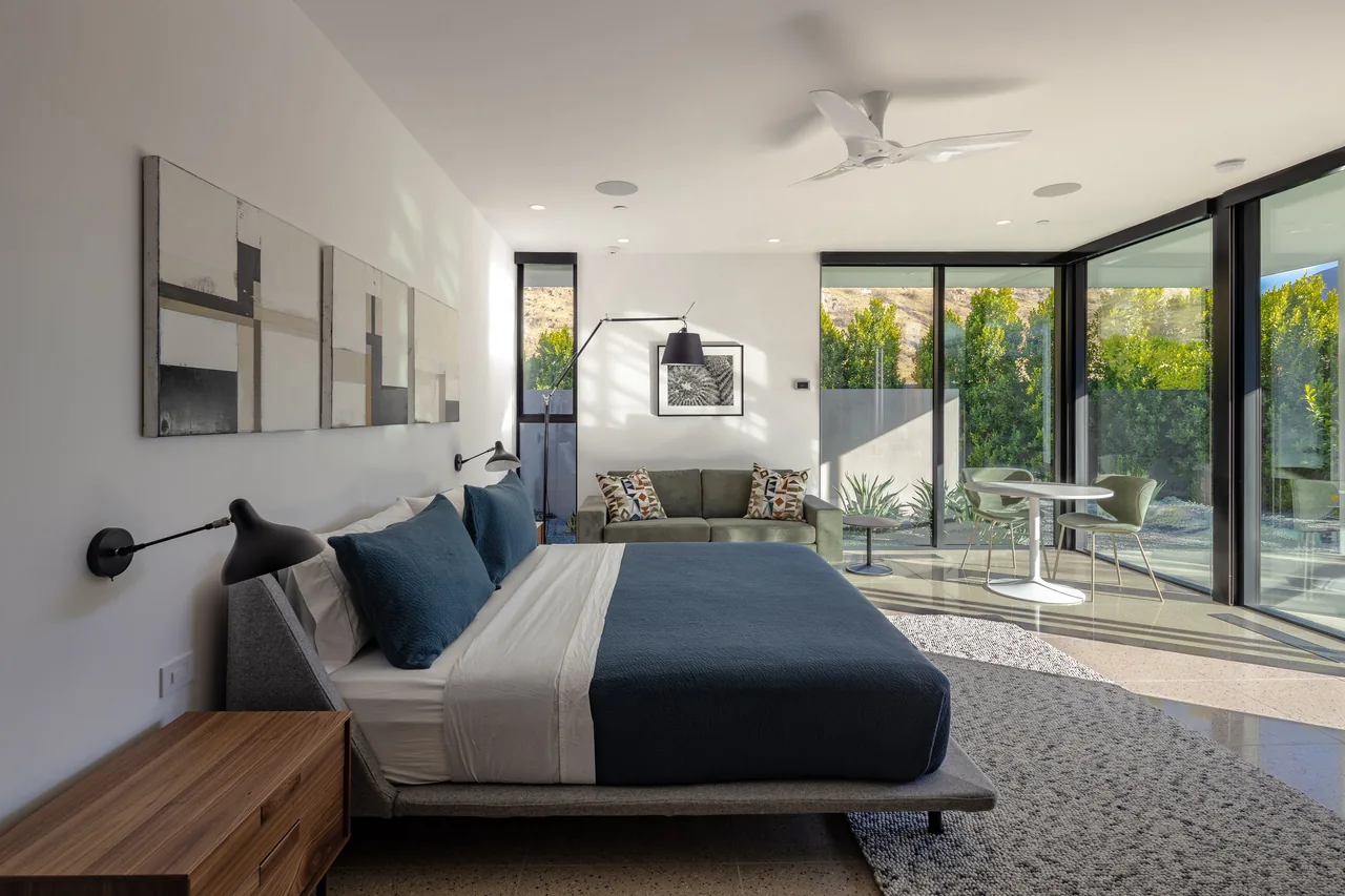Bedroom in the Sky Ridge project featuring floor-to-ceiling glass windows with a view of the outdoor patio and greenery.