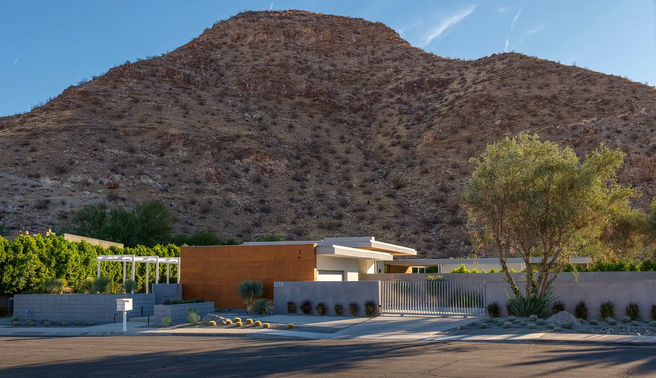 Sky Ridge project by o2 Archtecture features a flat-roofed house clad in wood siding next to a dry mountain landscape.