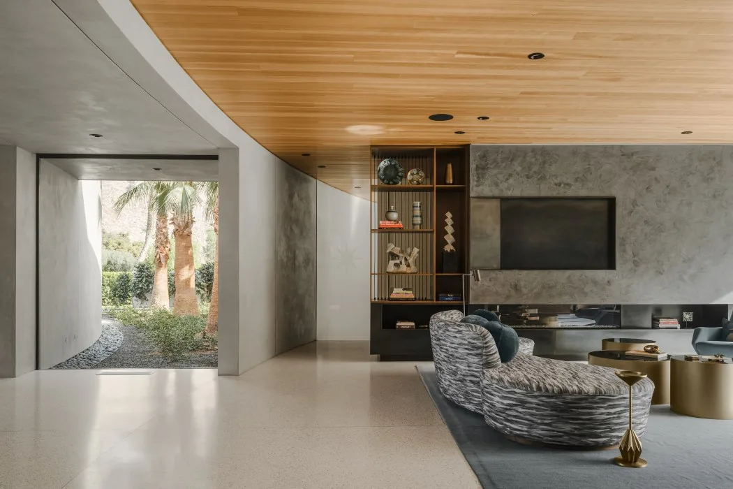 Living room with curved wall and ceiling, built-in shelving, and a patterned curved sofa seating.
