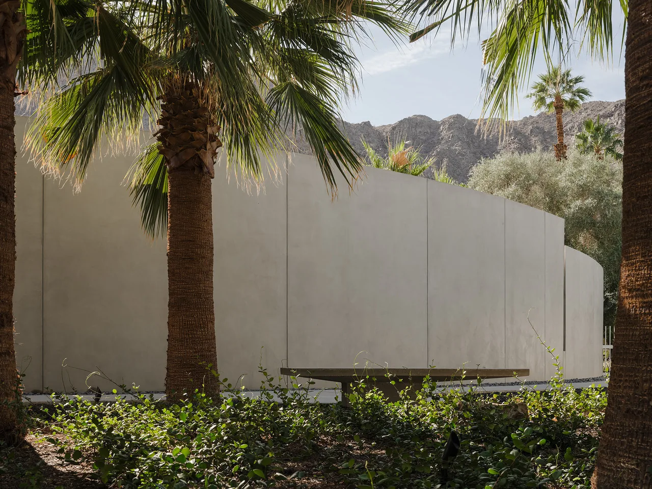 The Eldorado Tres project features a curved stucco wall surrounded by desert landscaping and palm trees.