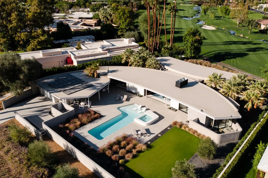 Eldorado Tres by o2 Architecture features a curved flat roof and a pool with integrated seating adjacent to a green lawn.