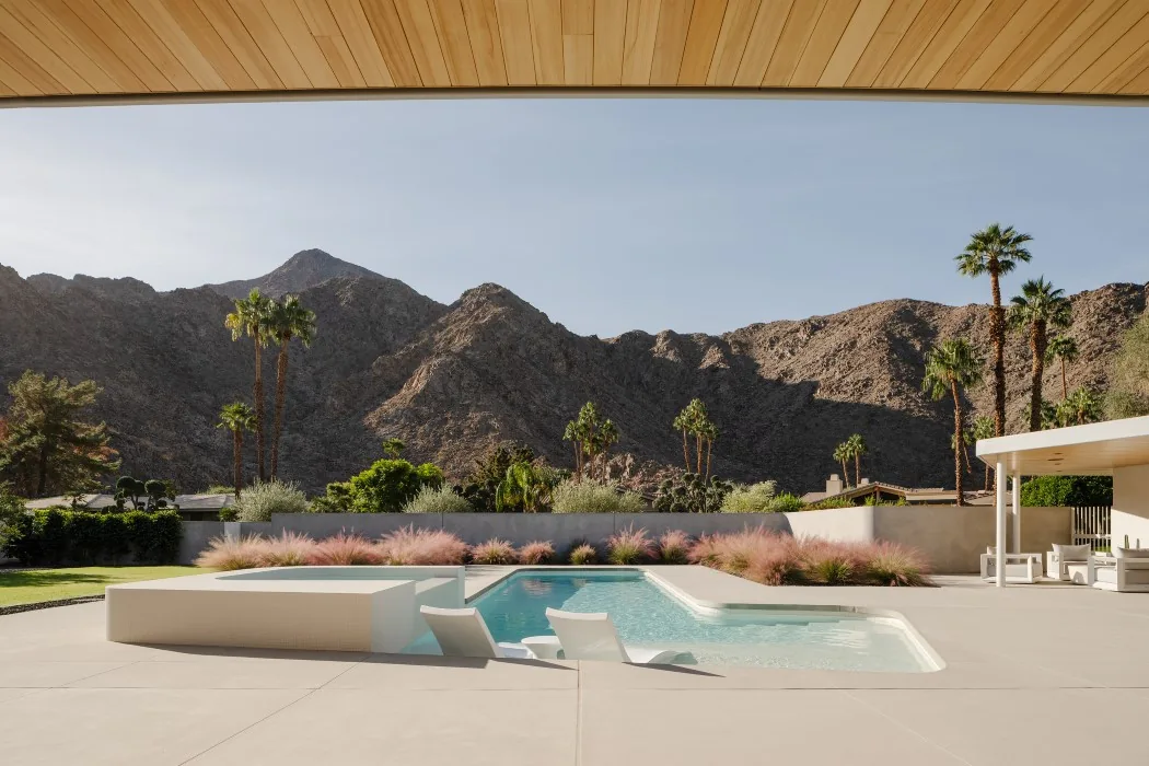 Outdoor living space with a pool, lounge chairs, and desert mountain views at Eldorado Tres project.