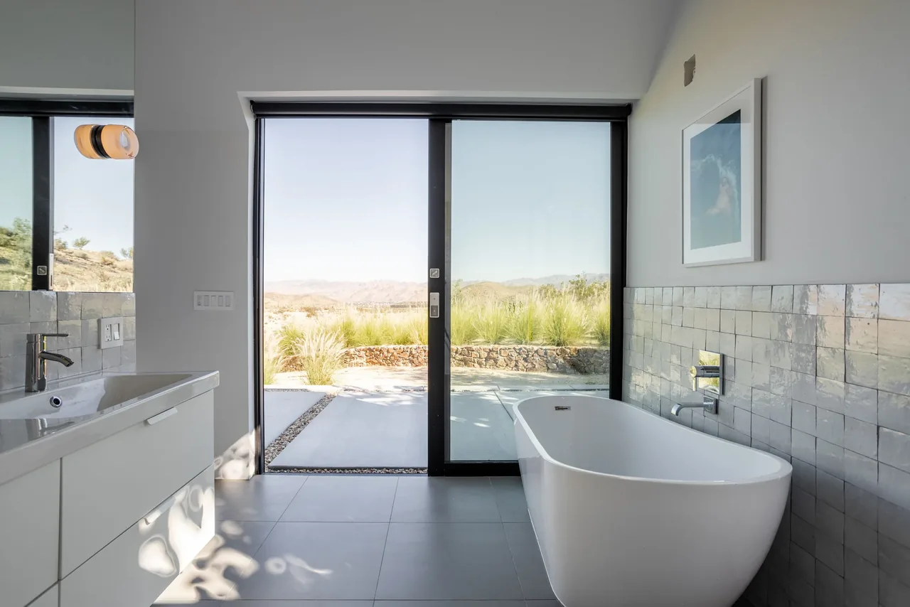 Bathroom with freestanding tub facing sliding glass door to outdoor landscape in the Alta Guesthouse.