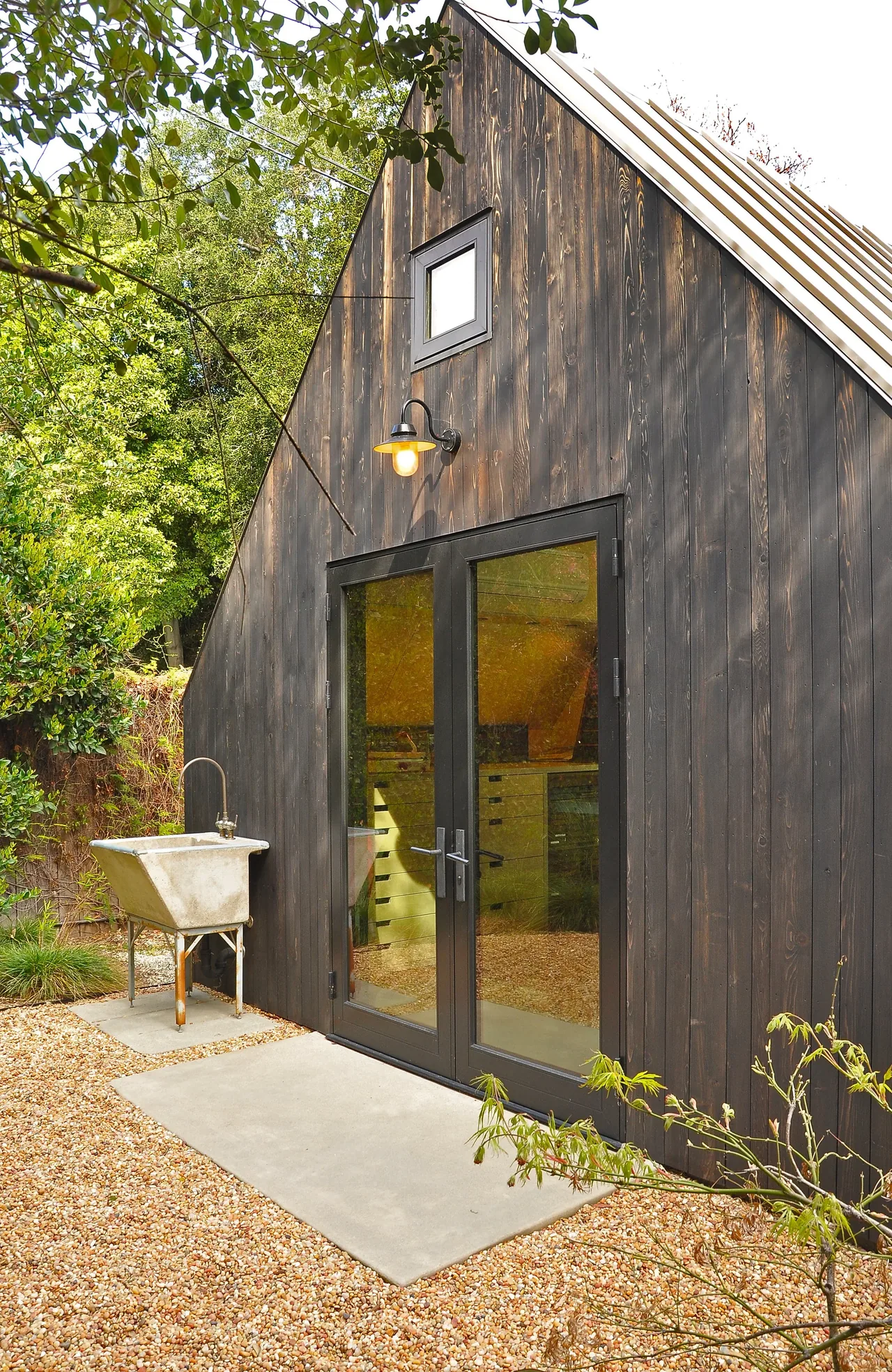 Exterior view of Bellefontaine Studio featuring black wooden siding, glass double doors, and a small upper window.