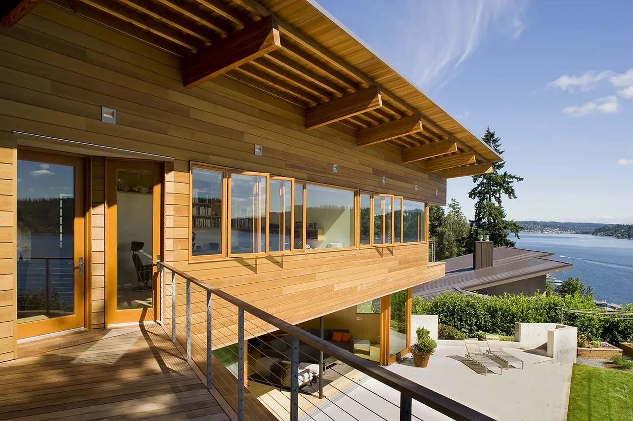 The Y House features wood siding, an angled roof overhang, and overlooks a scenic lake in Seattle.