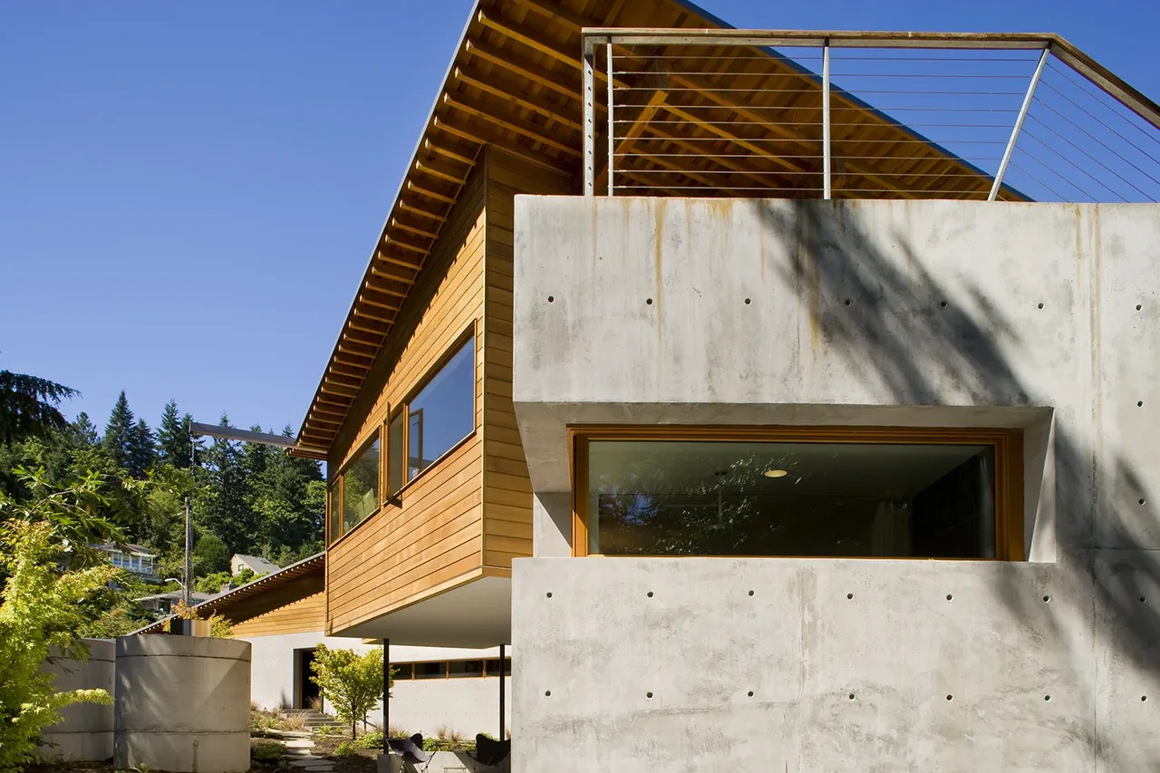 Exterior of Y House features horizontal wood paneling above board-formed concrete walls and an angled roof overhang.