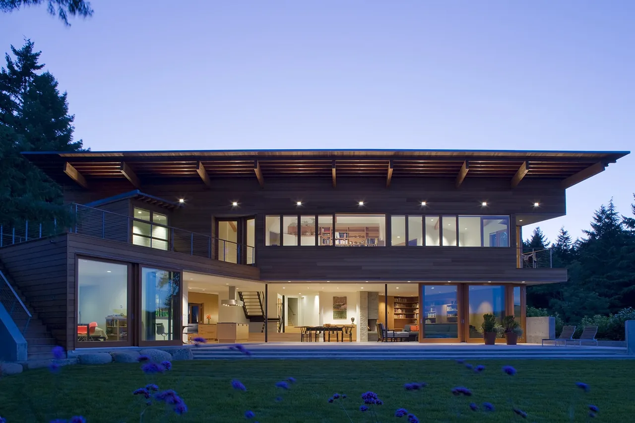 Y House features horizontal wood paneling and large windows under an angled roof overhang by Peter Cohan Architect in Seattle.