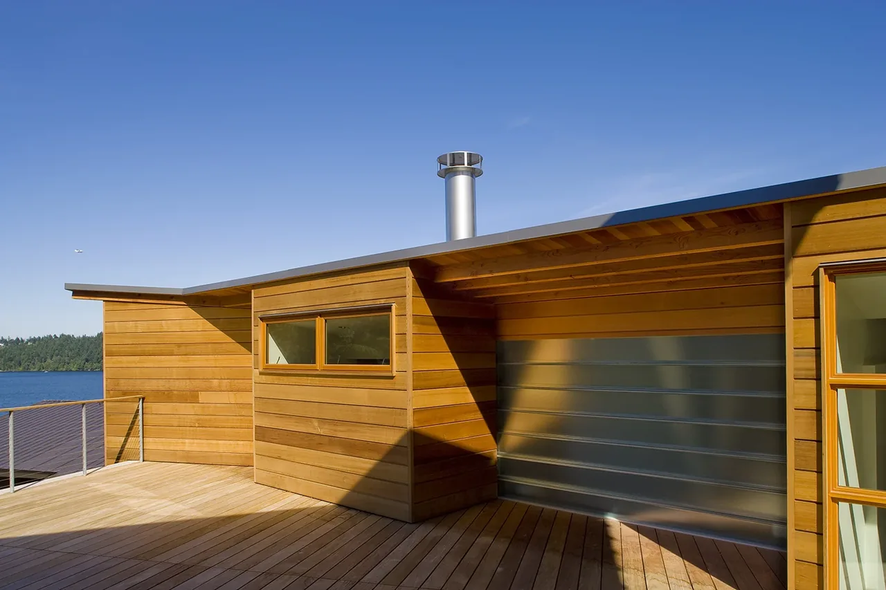 Exterior of Y House features horizontal narrow windows and wood siding with a lake view and angled roof overhang.