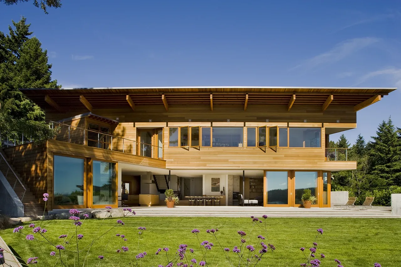 The Y House by Peter Cohan Architect features wooden siding, expansive glazing, and an angled roof overhang.
