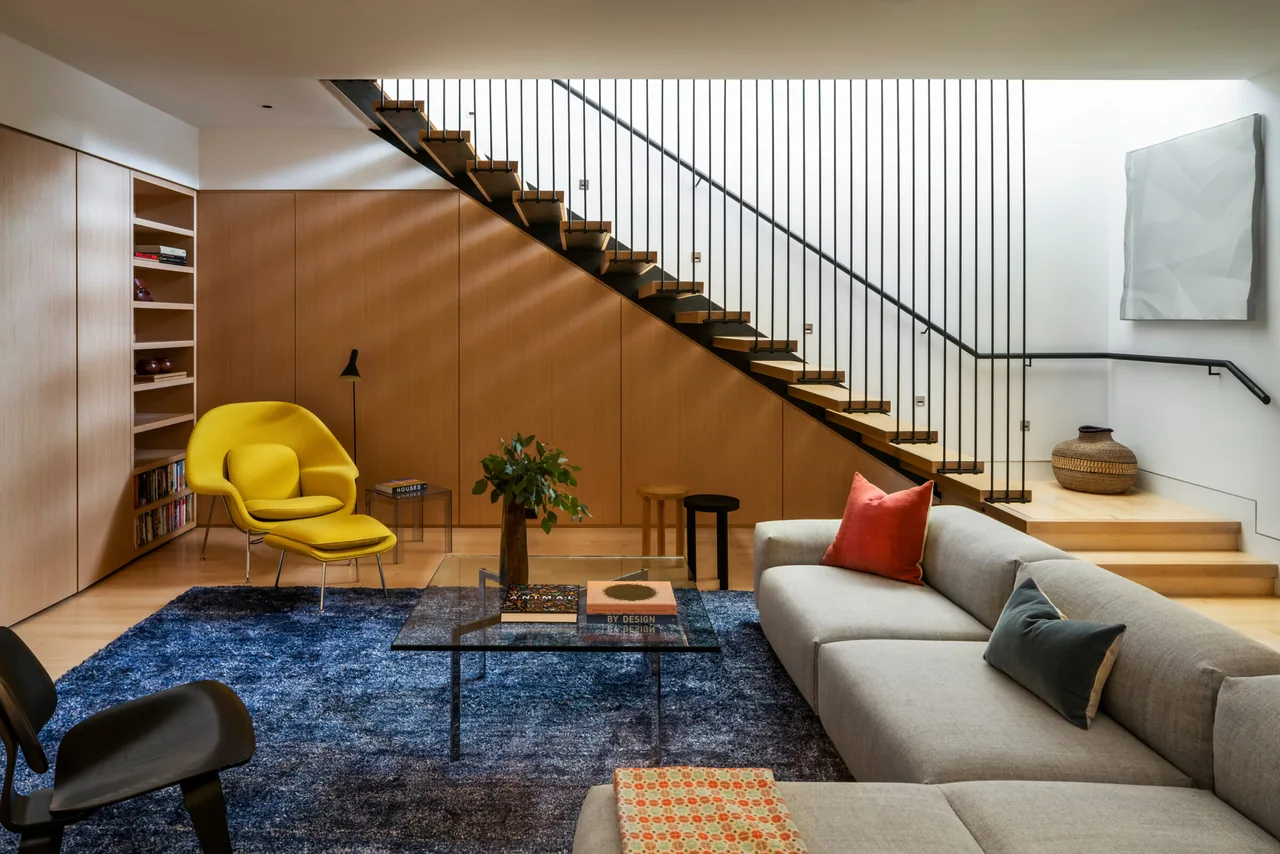 Lower-level lounge with modern furniture, featuring stairs in the background.