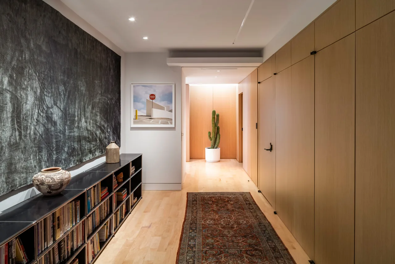Hallway with a blackboard, half-height bookshelf and wood walls.