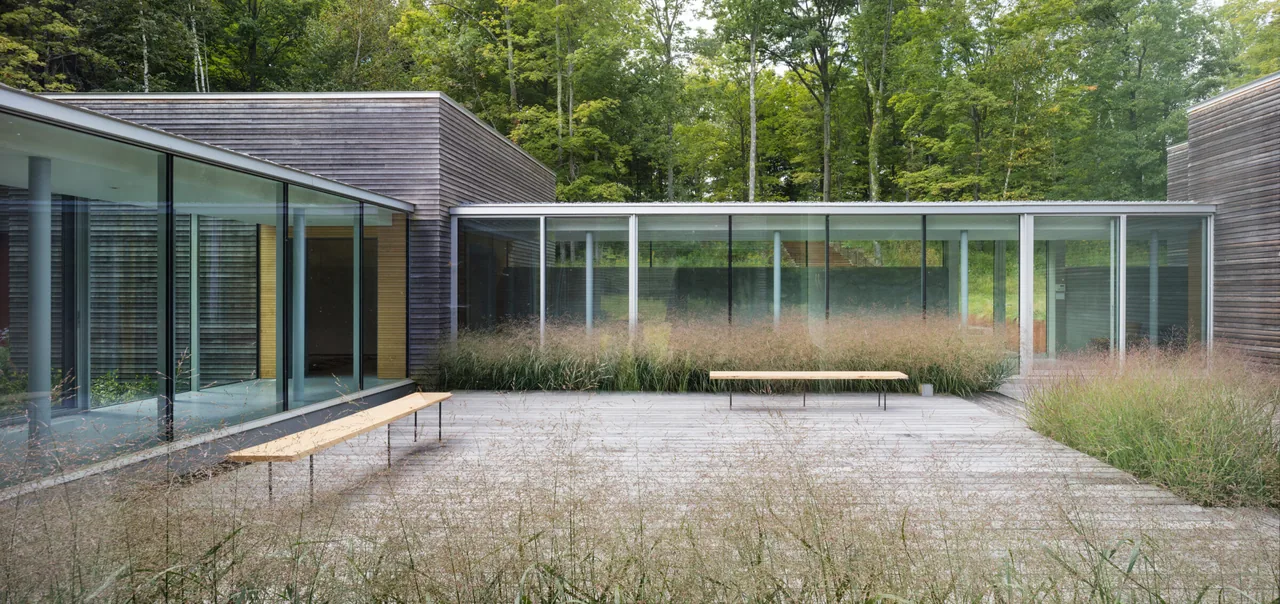 The Artist Retreat features an open courtyard with floor-to-ceiling glazing and natural wood siding.