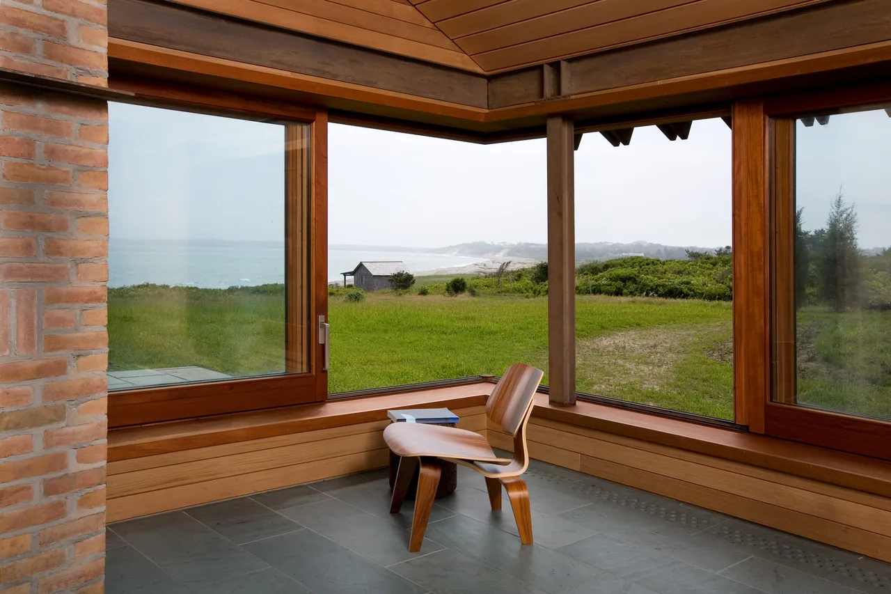 Corner seating nook in Vineyard Residence with large wood-framed windows offering ocean views.