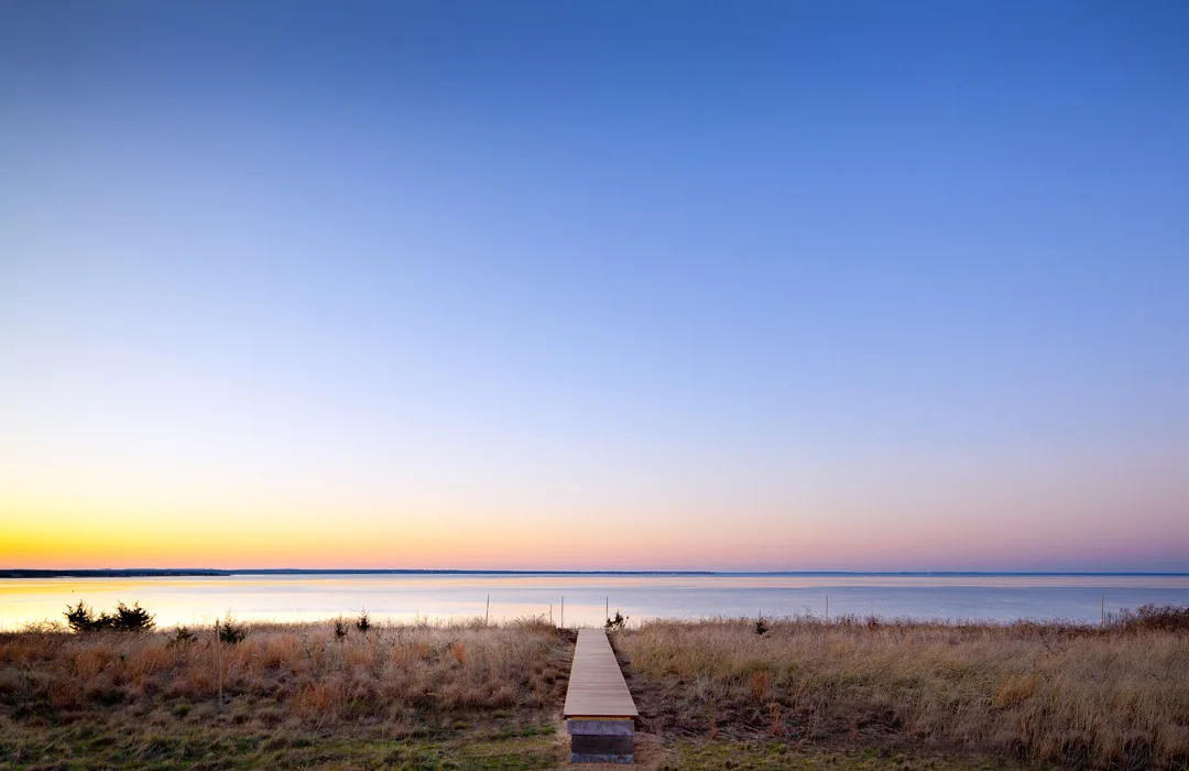 Sunset view over the waterfront from a wooden boardwalk at the Island Residence site.