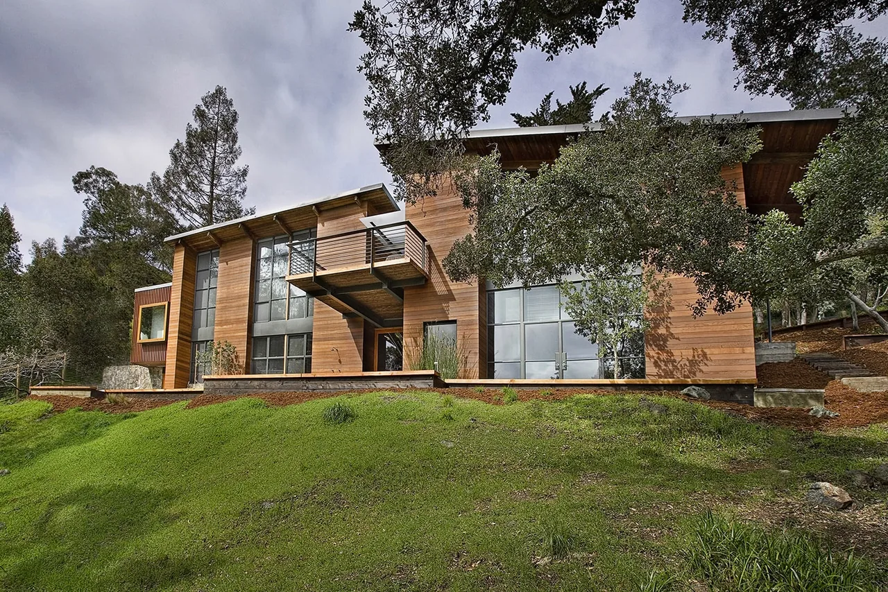 The Lovell Residence features a wood-clad exterior with large windows and a balcony with glass railing.