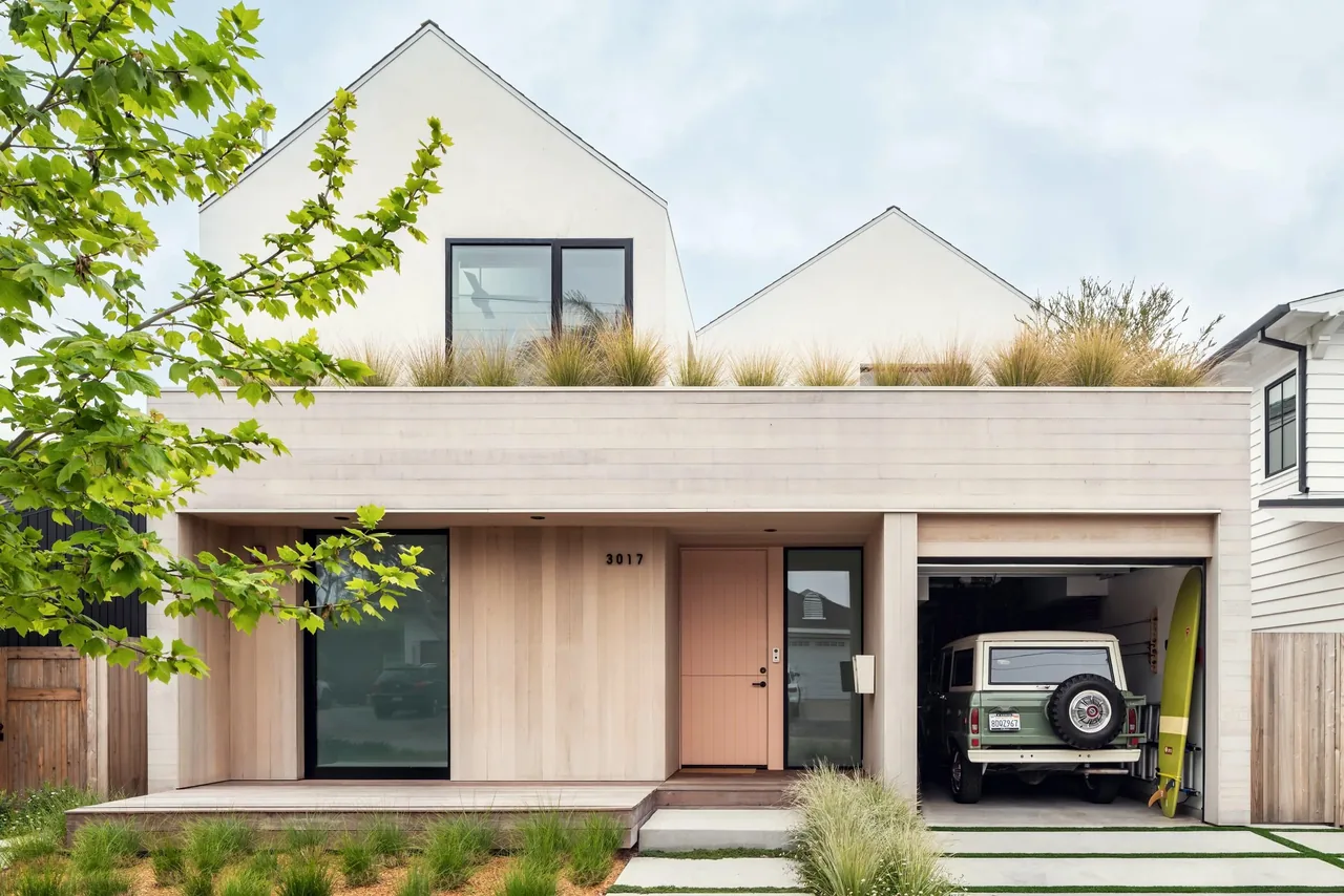Oak Avenue House features light wood siding with black window frames and a flat roof with greenery.