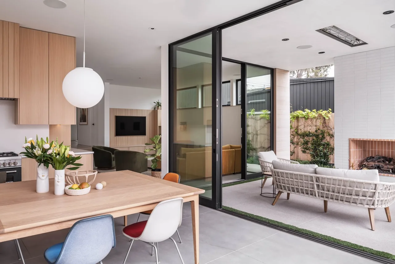 The Oak Avenue House features an open dining-kitchen area that seamlessly connects to a covered patio with an outdoor fireplace.