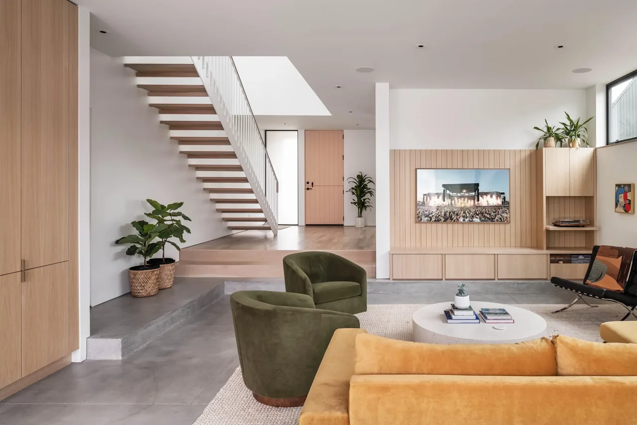 Living room in Oak Avenue House features floating stairs, wood paneling, and minimalist furnishings.