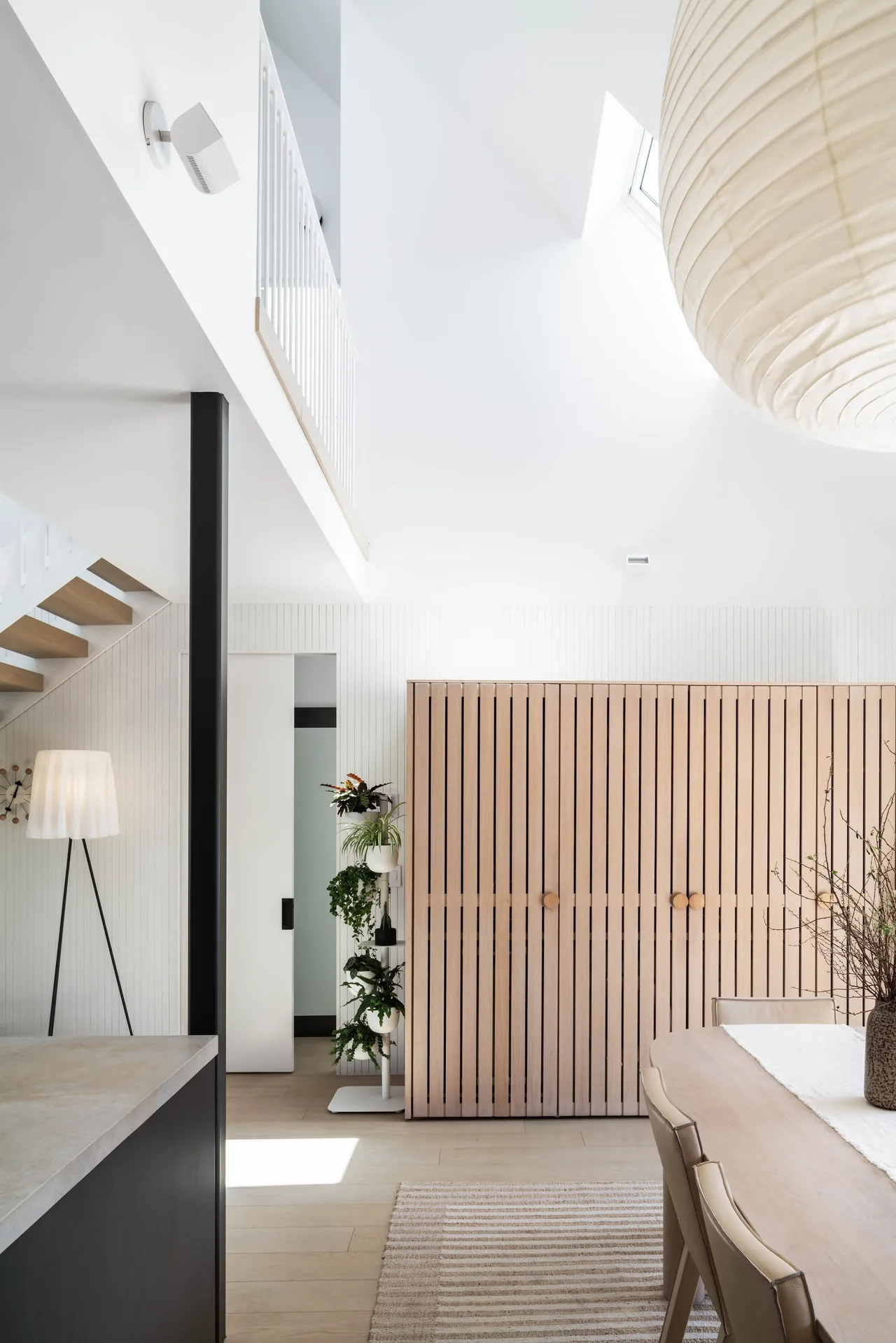 Open indoor space features vertical wood paneling, a large wooden slatted cabinet, and a paper lantern pendant light.