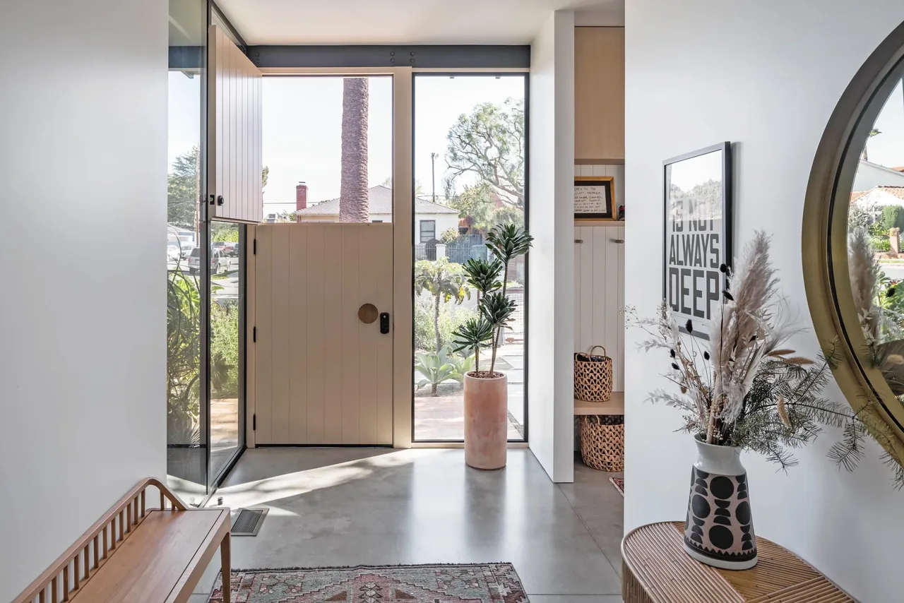 The Glencoe Avenue House features a modern entry with a half Dutch door and floor-to-ceiling glass panels.
