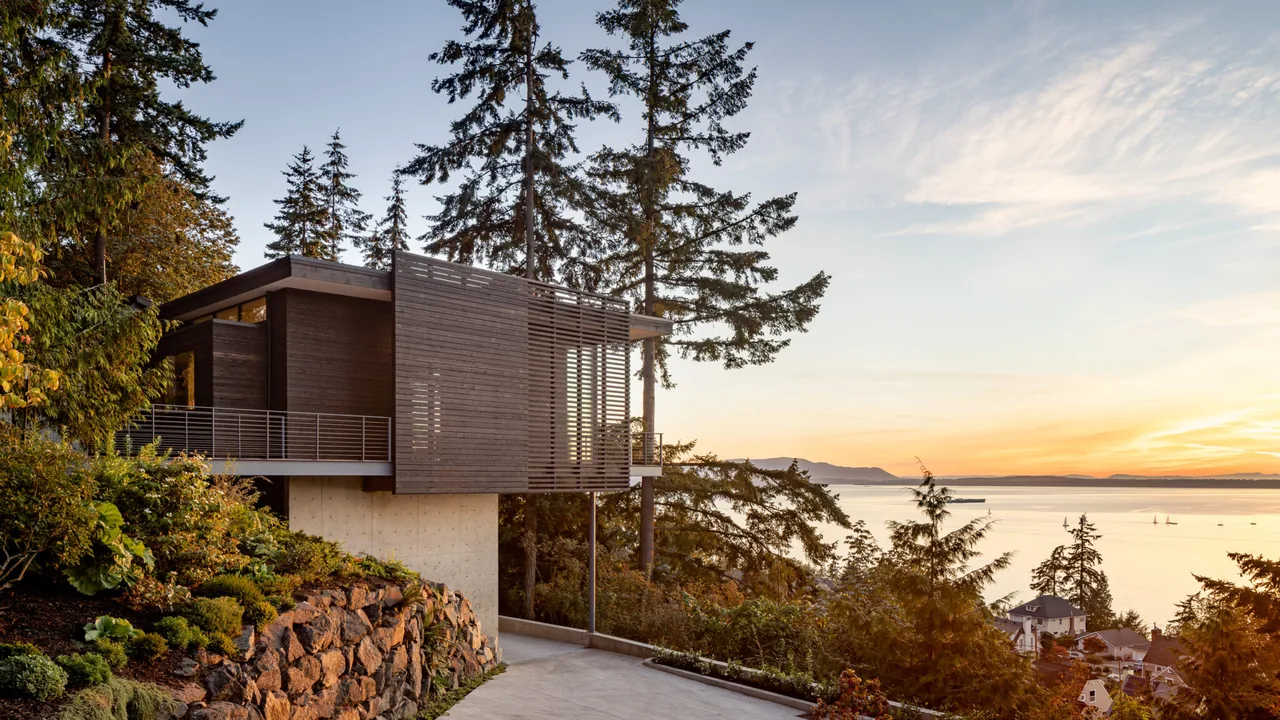 Nest project by Replinger Hossner Architects features wood siding and a horizontal wood slat screen with a water view.