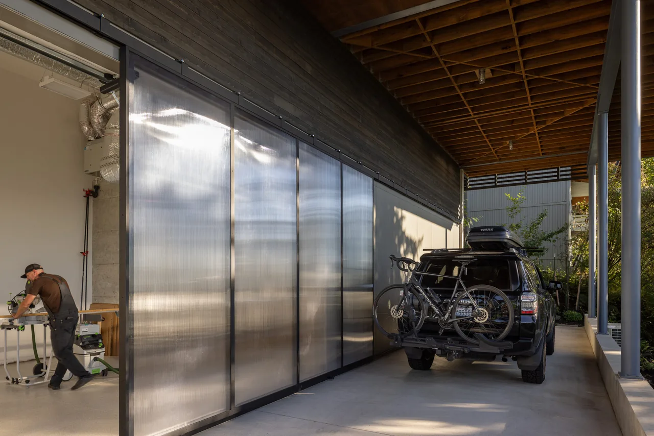 Covered exterior carport with translucent sliding panels and exposed wood ceiling beams.