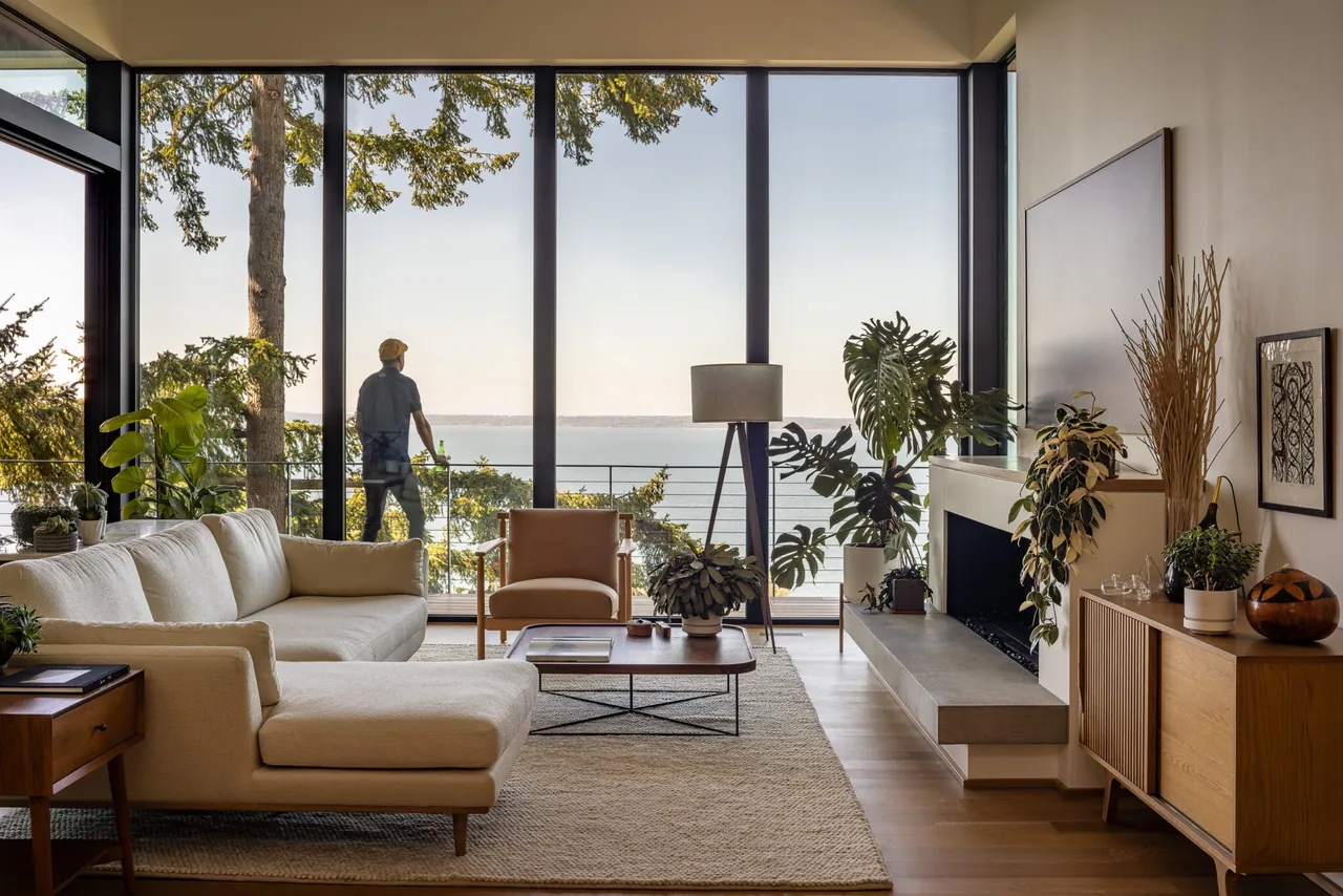Living room with floor-to-ceiling windows and water view at Nest by Replinger Hossner Architects.
