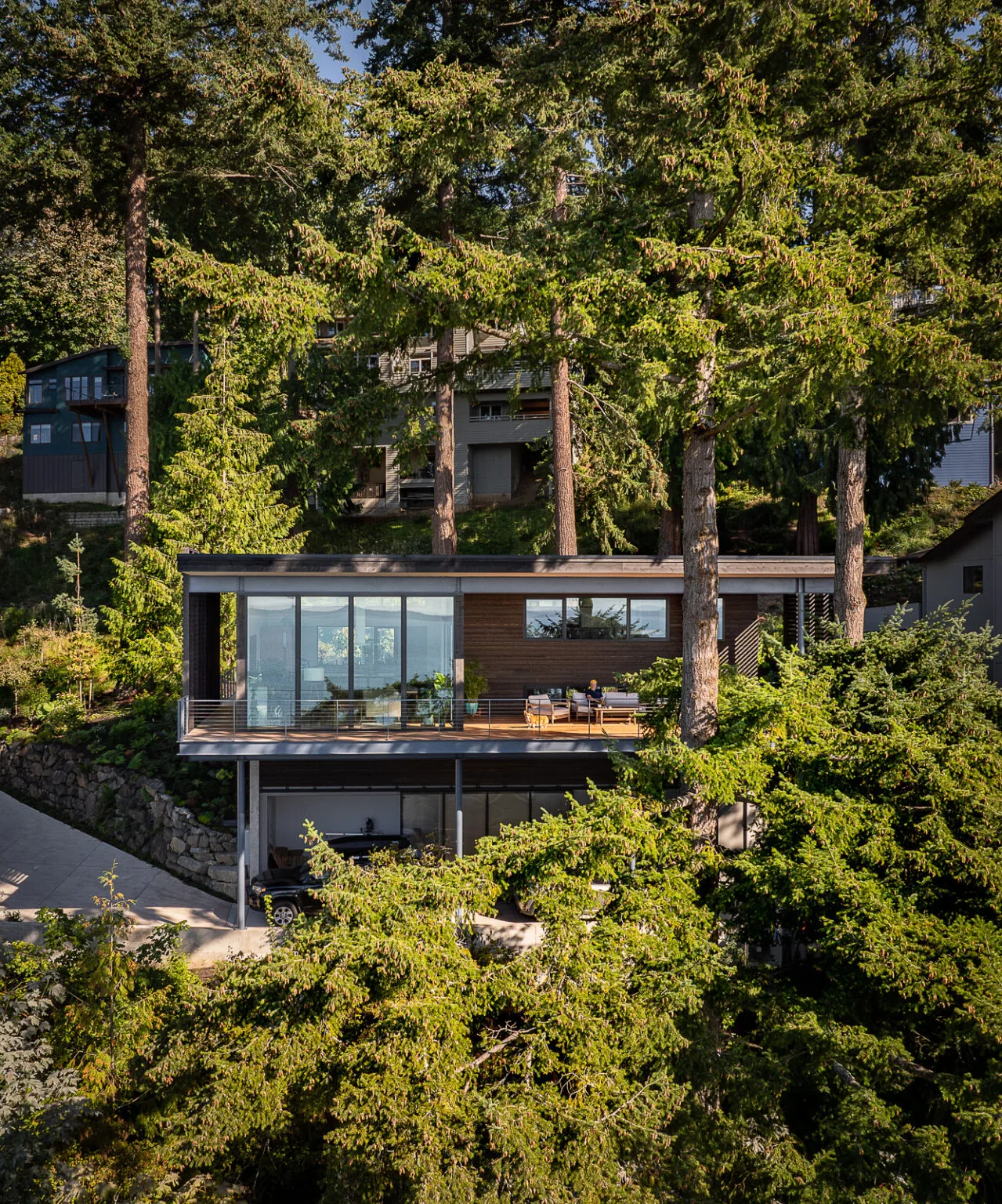Nest project by Replinger Hossner Architects features a modern hillside home with floor-to-ceiling glazing and wood siding.