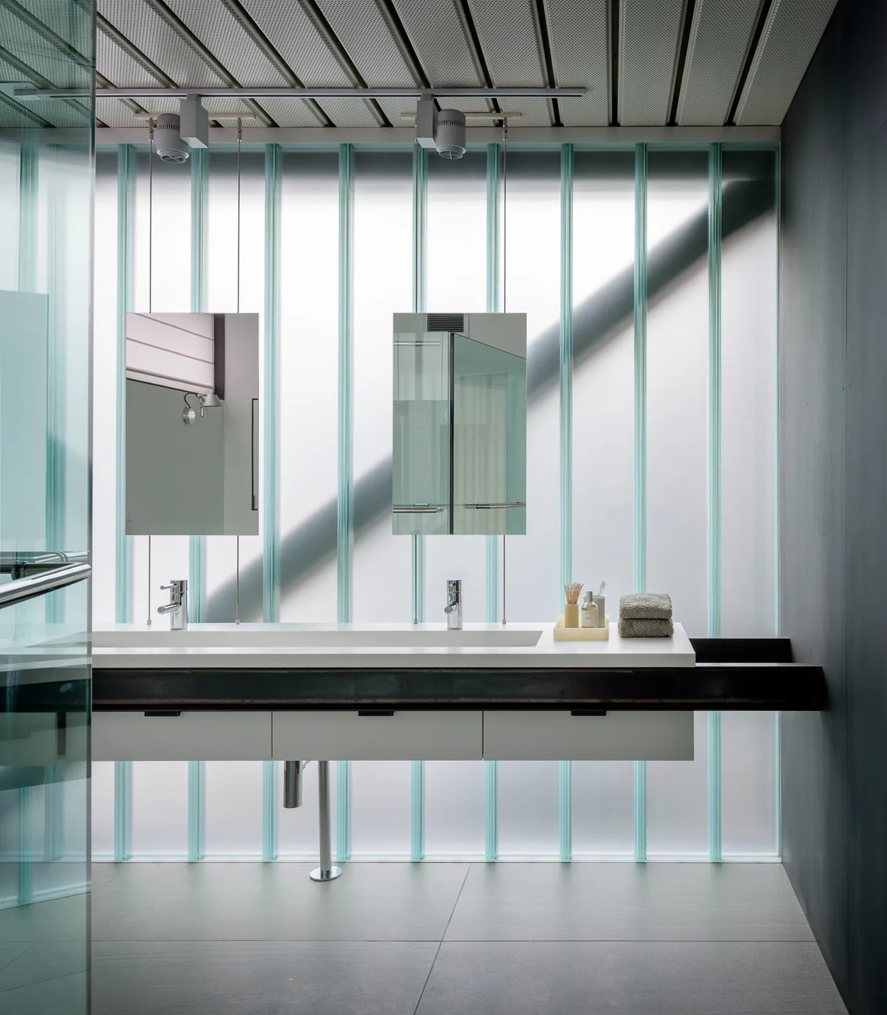 Bathroom in the DMG House features a double vanity with floating sink and frosted glass accent wall.