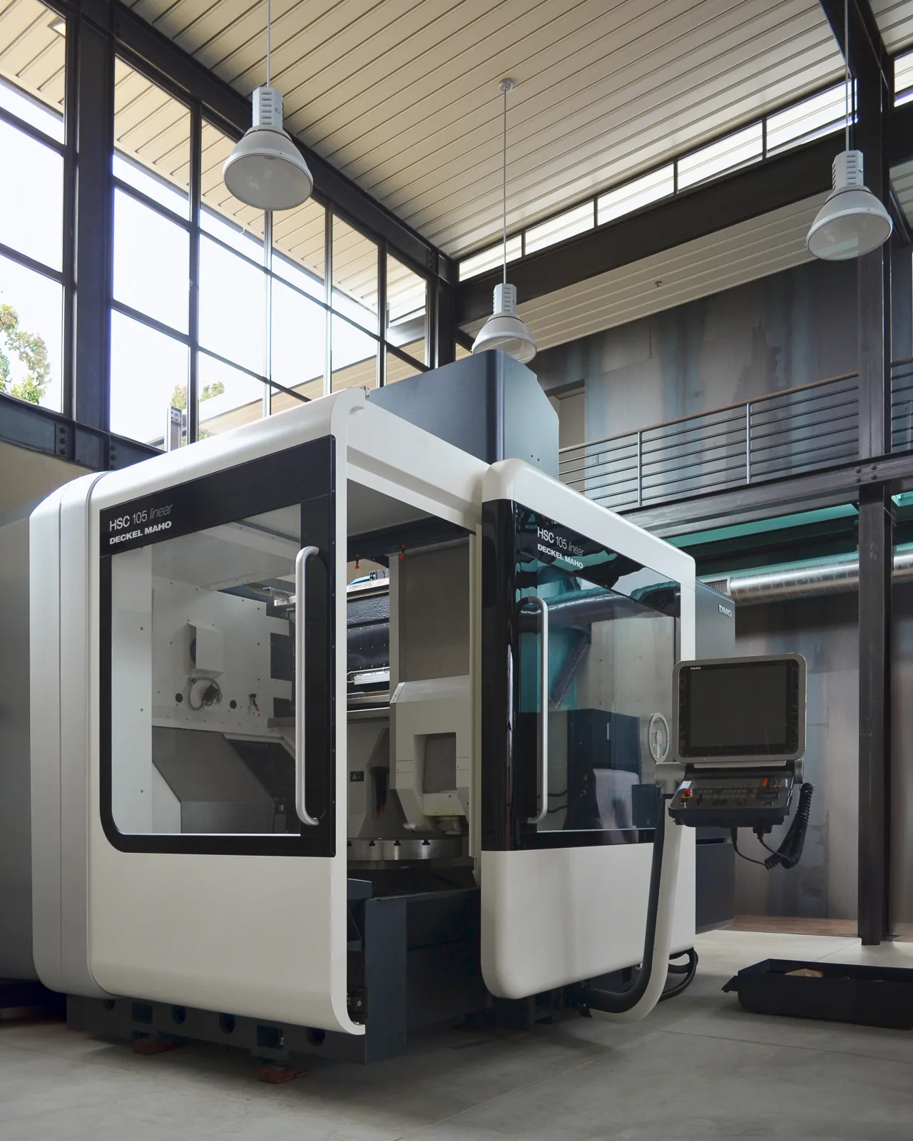 Interior view of a facility featuring industrial machinery and a metal balcony with large glazing.