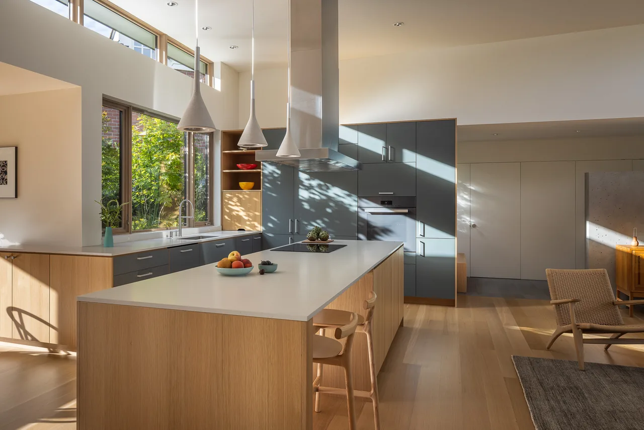 Daylit kitchen in the MADISON project features a large island with wood and gray cabinets under clerestory windows.