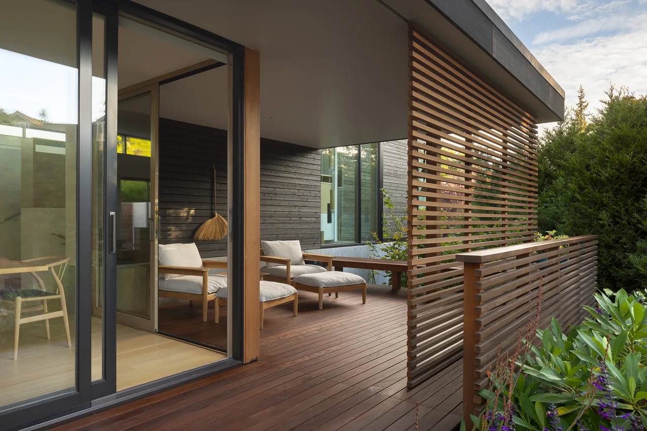 Outdoor living space with horizontal wood slat privacy screens and sliding glass doors opening to interior.