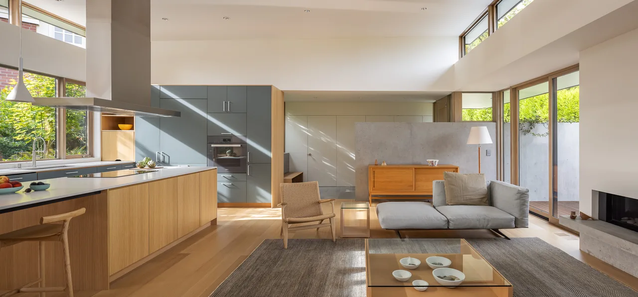 Open kitchen and living area featuring wood floors, gray kitchen cabinets, clerestory windows, and sliding glass doors to outdoor space.