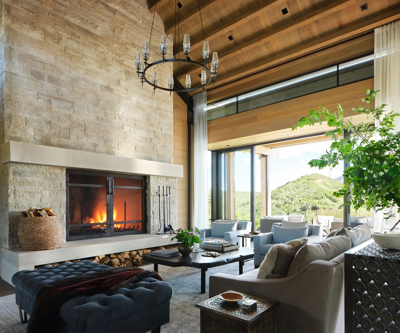 Living room of Morning Star Residence features a stone fireplace and large windows framing mountain views.