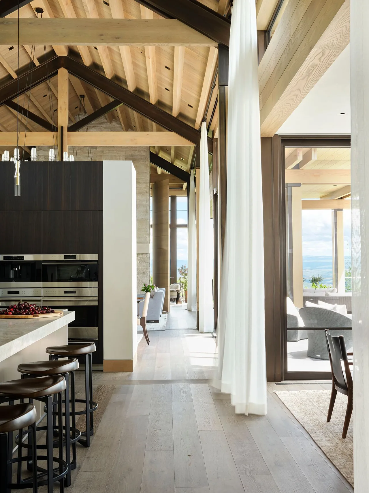 Morning Star Residence showcases exposed wood beams and sheer curtains in the kitchen and adjacent hallway with mountain views.