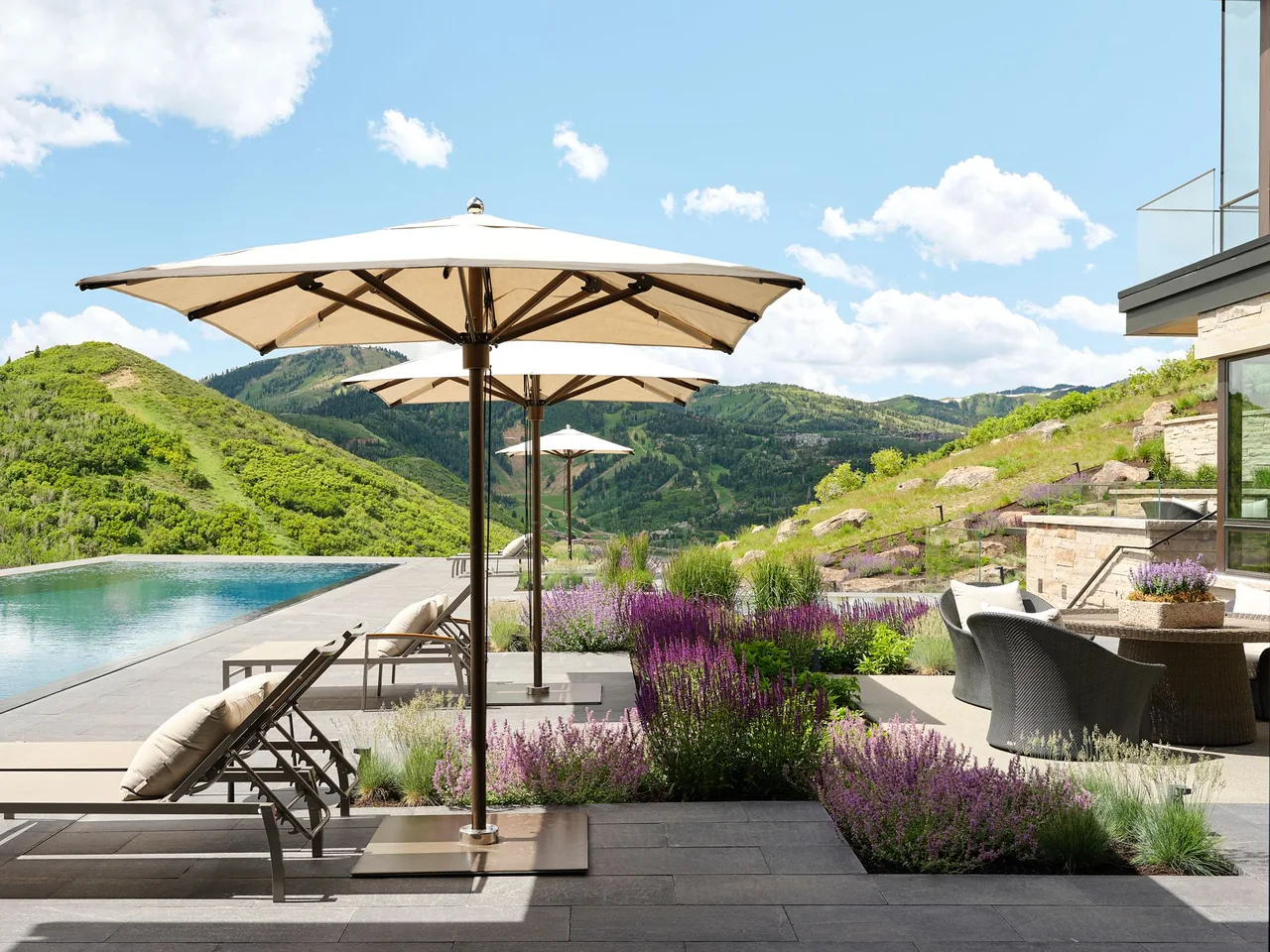 Patio with lounge chairs, umbrellas, and an infinity pool at Morning Star Residence with mountain views.