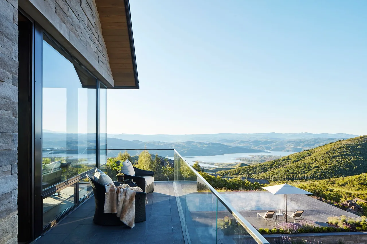 Balcony with seating and glass railing at Morning Star Residence with views of hills and a lake.