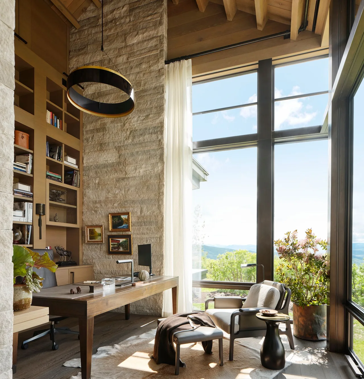 Morning Star Residence office with stone walls, wood ceiling, and large windows showcasing a mountain view.