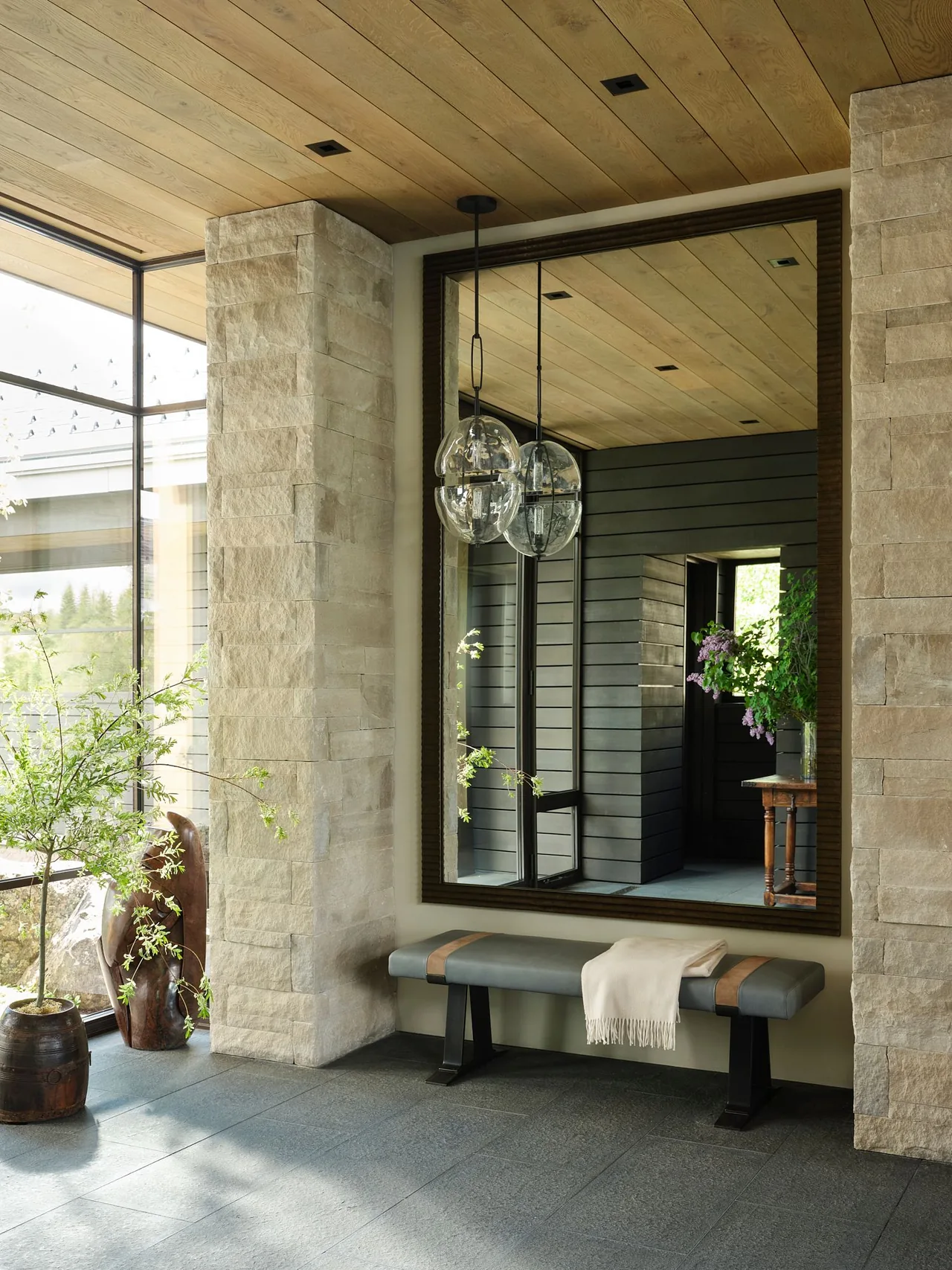 Entry space of Morning Star Residence featuring stone pillars and a large framed mirror reflecting an interior hallway.