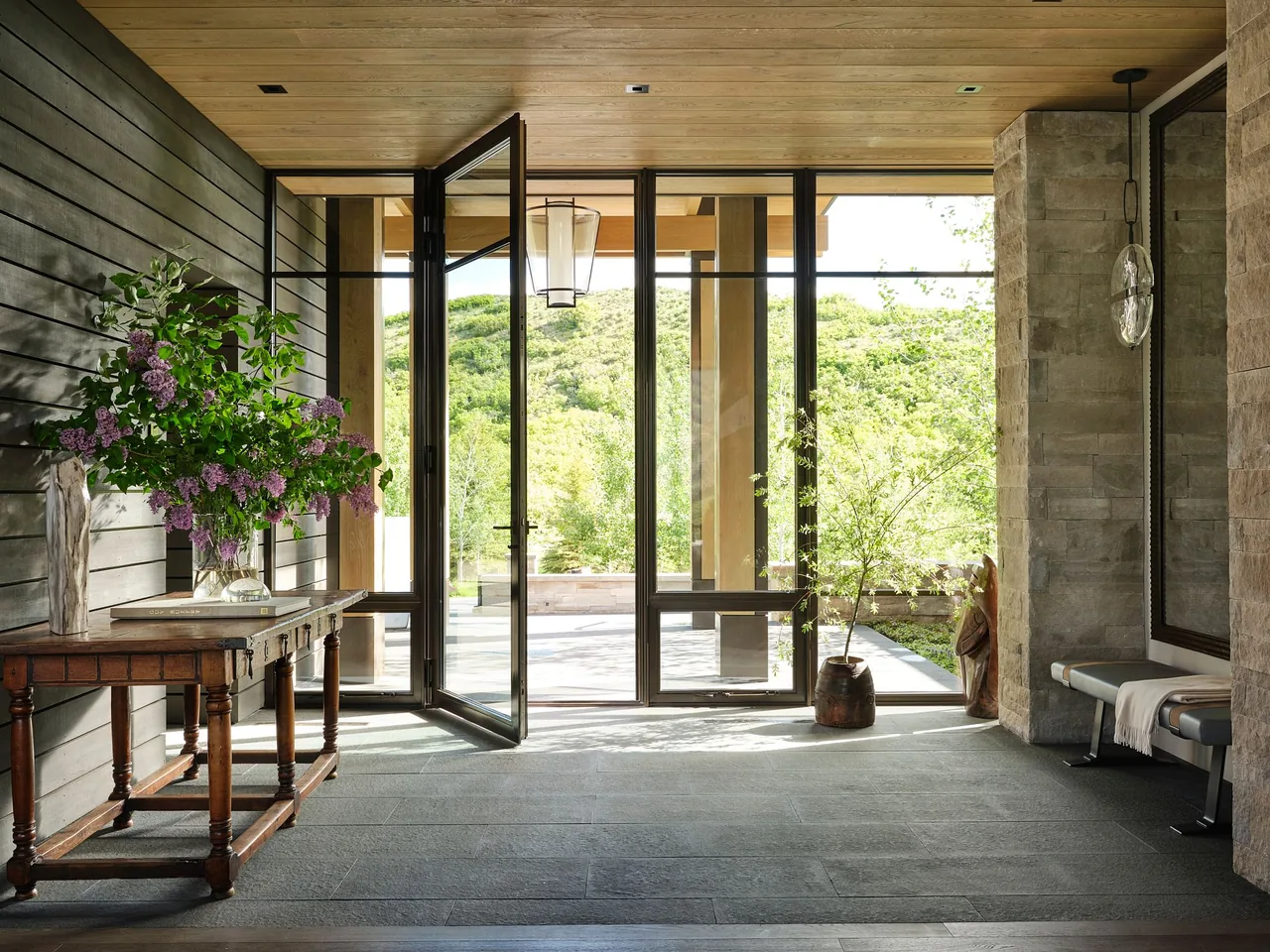 Entry area of Morning Star Residence with wood and stone finishes and folding glass doors to outside.