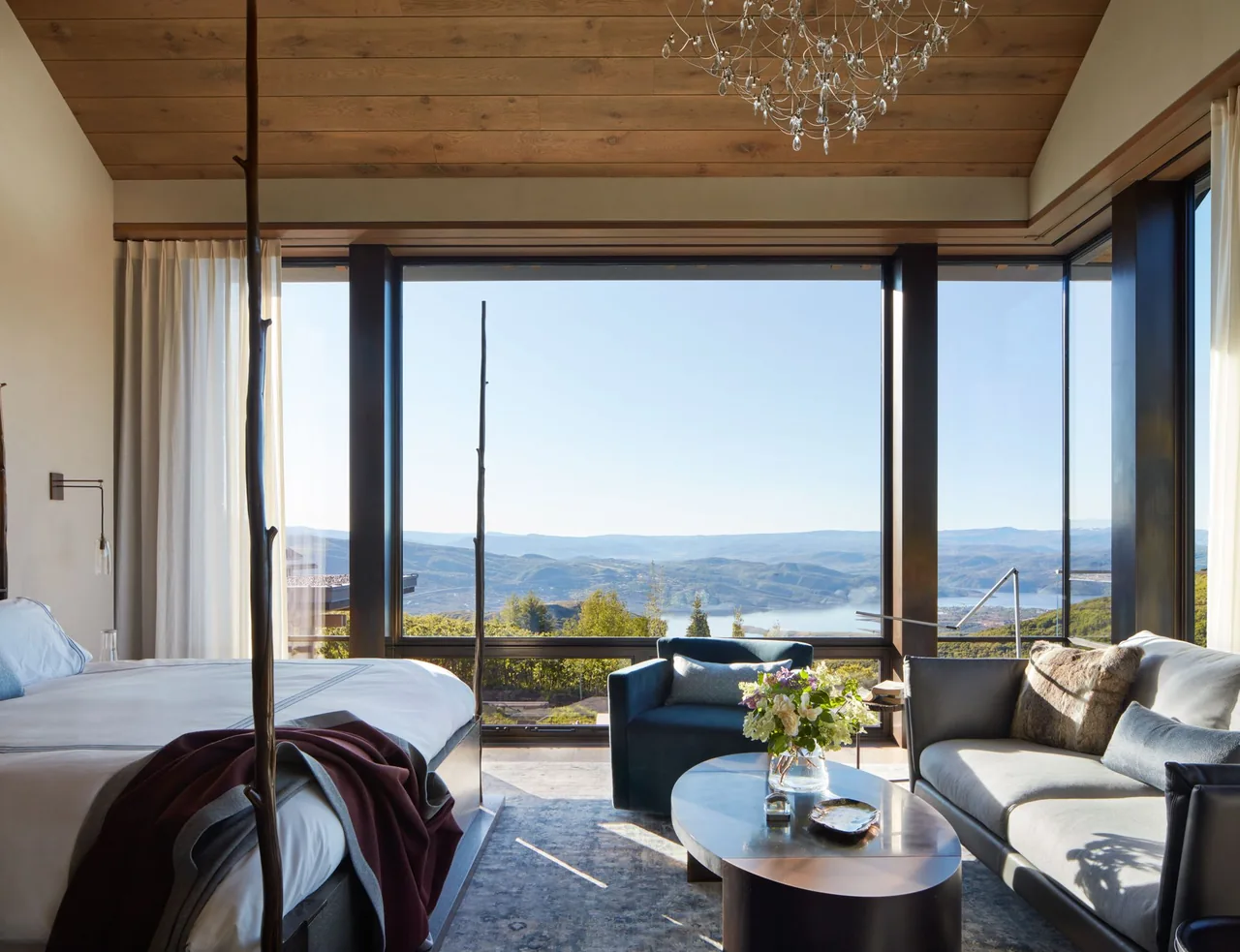 The Morning Star Residence bedroom features floor-to-ceiling windows with mountain views, wood-paneled ceilings, and a modern sitting area.